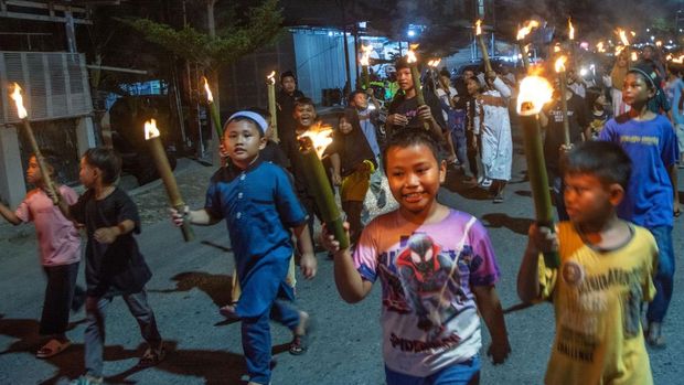 Sejumlah anak membawa obor berpawai mengiringi arakan usungan untaian makanan berkeliling kampung pada tradisi Lebaran Mandura di Kampung Baru, Palu, Sulawesi Tengah, Selasa (16/4/2024). Lebaran Mandura adalah tradisi tahunan yang digelar warga setelah hari ketujuh lebaran Idul Fitri dengan mengarak Mandura atau makanan khas lebaran  terbuat dari tiga jenis beras ketan yang dibungkus dengan daun pisang. ANTARA FOTO/Basri Marzuki