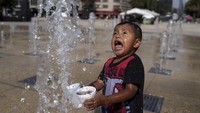 Tampak anak kecil kegirangan bermain air.