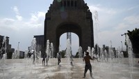 Sejumlah warga bermain-main di air mancur di dasar Monumen Revolusi di Mexico City, Selasa (16/4/2024).