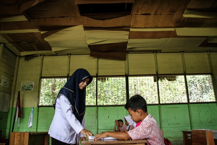 Seorang guru menyampaikan materi kepada siswa saat kegiatan belajar mengajar di kelas dengan kondisi plafon rusak di SD Negeri Petuk Katimpun 01 Palangka Raya, Kalimantan Tengah, Rabu (17/4/2024). Menurut kepala sekolah setempat, sejak lima tahun terakhir sebanyak tiga ruang kelas di sekolah tersebut mengalami kerusakan pada bagian dinding dan plafon sehingga membahayakan kegiatan belajar mengajar. ANTARA FOTO/Auliya Rahman/rwa.