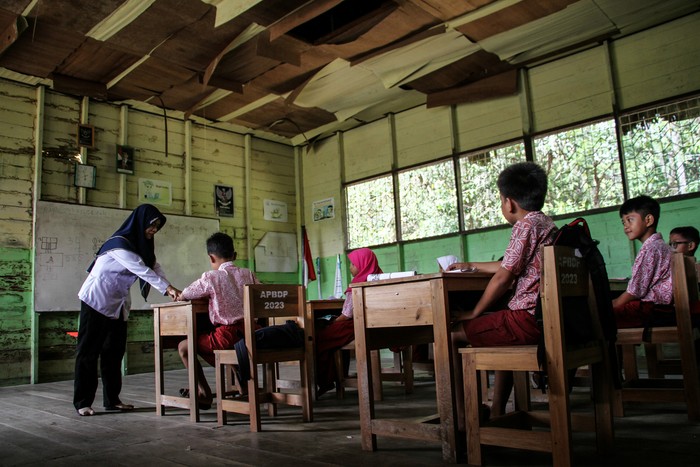 Seorang guru menyampaikan materi kepada siswa saat kegiatan belajar mengajar di kelas dengan kondisi plafon rusak di SD Negeri Petuk Katimpun 01 Palangka Raya, Kalimantan Tengah, Rabu (17/4/2024). Menurut kepala sekolah setempat, sejak lima tahun terakhir sebanyak tiga ruang kelas di sekolah tersebut mengalami kerusakan pada bagian dinding dan plafon sehingga membahayakan kegiatan belajar mengajar. ANTARA FOTO/Auliya Rahman/rwa.