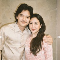 Tampil sederhana mengikuti sang istri, Baskara Mahenra rupanya juga mengenakan baju yang dipinjam dari mertuanya, Triawan Munaf. Terlihat Baskara mengenakan kemeja lengan panjang berwarna soft gold. Foto: Instagram/@sherinamunaf