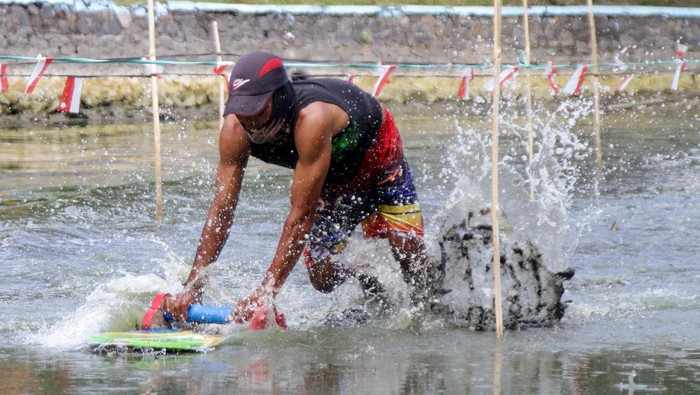 Peserta mendorong papan Ski Lot atau selancar lumpur di kolam Desa Tambaklekok, Lekok, Pasuruan, Jawa Timur, Rabu (17/4/2024). Ski Lot merupakan tradisi yang dilakukan masyarakat sekitar pesisir laut dalam merayakan Lebaran Ketupat. ANTARA FOTO/Umarul Faruq/rwa.
