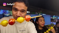 Tak ketinggalan juga Fadly menikmati tanghulu, jajanan populer berupa sate buah-buahan yang dibalut dengan gula. Foto: YouTube Fadly Faisal
