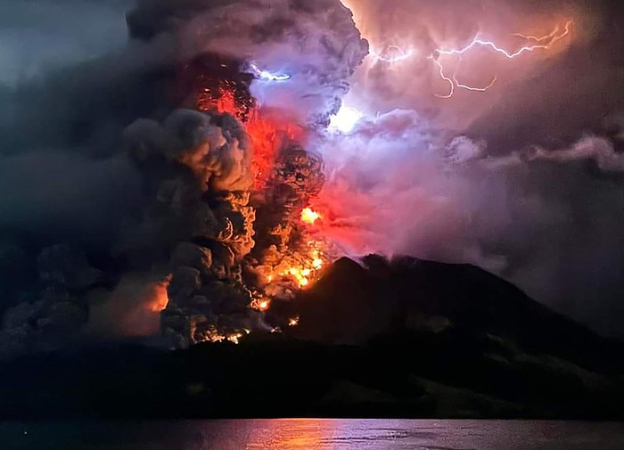 This handout photograph taken and released by the Center for Volcanology and Geological Hazard Mitigation on April 17, 2024, shows Mount Ruang spewing hot lava and smoke as seen from Sitaro, North Sulawesi. A volcano erupted several times in Indonesias outermost region overnight on April 17, forcing hundreds of people to be evacuated after it spewed lava and a column of smoke more than a mile into the sky. (Photo by Handout / Center for Volcanology and Geological Hazard Mitigation / AFP)