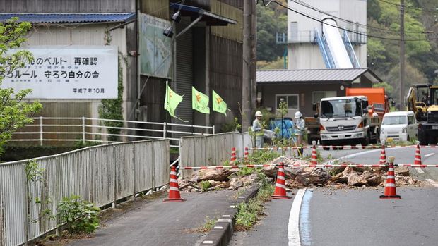 Workers look at a closed off section of the national highway after rocks fell across the road when a 6.3 magnitude earthquake hit southern Japan late the night before, in the city of Ozu, Ehime prefecture on April 18, 2024. Eight people were reported injured on April 18 after a 6.3-magnitude earthquake struck at 11:14pm local time the night before off southwestern Japan, but there appeared to be no major damage or tsunami. (Photo by JIJI Press / AFP) / Japan OUT