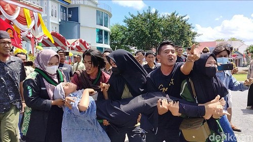 Mahasiswa mengevakuasi salah satu korban pingsan saat demonstrasi soal harga jagung anjlok di Kantor Bupati Dompu, Kamis (18/4/2024). (Faruk Nickyrawi/detikBali)