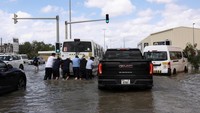 Sejumlah orang mendorong mobil yang mogok akibat banjir. Para ilmuwan iklim mengatakan bahwa kenaikan suhu global, yang disebabkan oleh perubahan iklim yang disebabkan oleh aktivitas manusia, menyebabkan terjadinya cuaca yang lebih ekstrem di seluruh dunia, termasuk curah hujan yang tinggi.