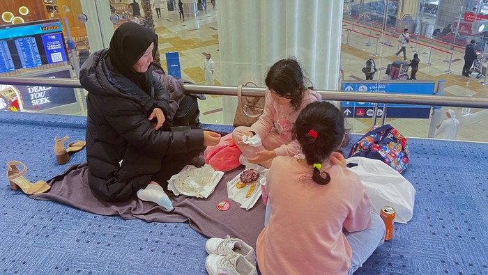 A woman and her daughters eat as they wait for their flight after a rainstorm hit Dubai, causing delays at Dubai International Airport, United Arab Emirates, April 17, 2024. REUTERS/Staff REFILE - QUALITY REPEAT