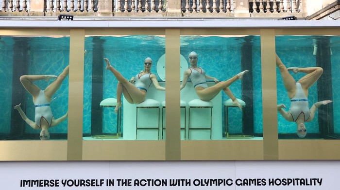 People watch as former British Olympic artistic swimmers Asha George and Katie Clark together with Sisy Wang and Emily Kuhl, all of Aquabatix, perform in a large water tank to mark 100 days before the 2024 Paris Olympic Games starts, at Covent Garden in London, Britain, April 17, 2024. REUTERS/Toby Melville