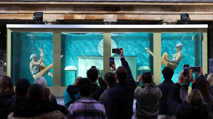 People watch as former British Olympic artistic swimmers Asha George and Katie Clark together with Sisy Wang and Emily Kuhl, all of Aquabatix, perform in a large water tank to mark 100 days before the 2024 Paris Olympic Games starts, at Covent Garden in London, Britain, April 17, 2024. REUTERS/Toby Melville