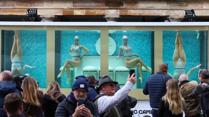 People watch as former British Olympic artistic swimmers Asha George and Katie Clark together with Sisy Wang and Emily Kuhl, all of Aquabatix, perform in a large water tank to mark 100 days before the 2024 Paris Olympic Games starts, at Covent Garden in London, Britain, April 17, 2024. REUTERS/Toby Melville