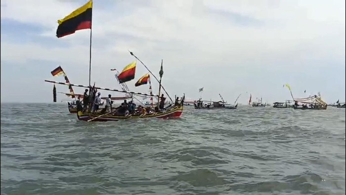 Puluhan perahu nelayan Desa Jatirejo, Lekok, Pasuruan menuju tengah laut untuk larung sesaji yang merupakan bagian dari tradisi petik laut