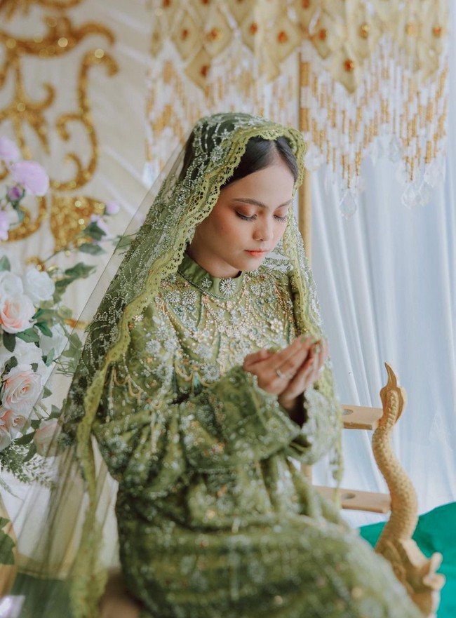 Dress berwarna hijau yang dikenakan oleh Putri itu tampak mewah dengan dipenuhi payet. Ia juga melengkapi penampilannya dengan kerudung berbahan tile yang juga dipenuhi dengan payet, senada dengan baju yang dikenakannya. Foto: Instagram/@da4_putri03