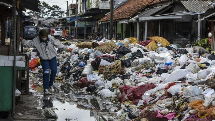 Warga melintasi tumpukan sampah yang menutupi akses jalan di Pembuangan Akhir Sementara,  Pasar Cikurubuk, Kota Tasikmalaya, Jawa Barat, Kamis (18/4/2024). Dinas Lingkungan Hidup Kota Tasikmalaya mencatat volume sampah di Kota Tasikmalaya selama Lebaran meningkat 20 persen atau sebanyak  230-240 ton per hari dibanding hari biasa mencapai 180-200 ton per hari. ANTARA FOTO/Adeng Bustomi/rwa.