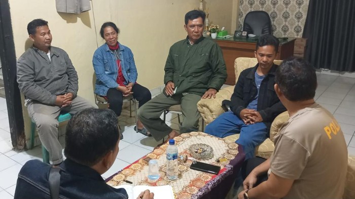 Dia (baju dan celana biru jaket hitam) saat menyerahkan diri ke kantor polisi.