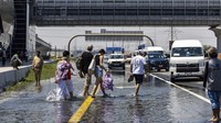 Orang-orang berjalan melewati banjir di jalan raya Sheikh Zayed Road di Dubai, Uni Emirat Arab, Kamis (18/4/2024).