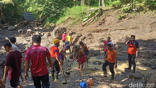 Petugas BPBD bersama warga saat membersihkan materiel tanah longsor yang menimpa akses jalan di wilayah Desa Gegelang, Kecamatan Manggis, Karangasem, Bali, Jumat (19/4/2024). (Foto: I Wayan Selamat Juniasa/detikBali)
