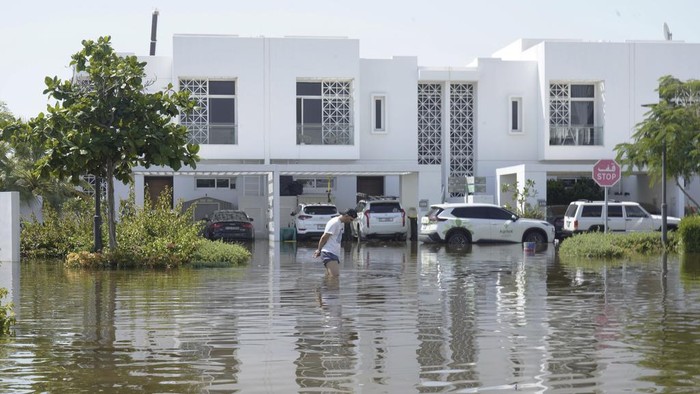 A man walks through floodwater in the Mudon neighborhood in Dubai, United Arab Emirates, Thursday, April 18, 2024. The United Arab Emirates attempted to dry out Thursday from the heaviest rain the desert nation has ever recorded — a deluge that flooded out Dubai International Airport and disrupted flights through the worlds busiest airfield for international travel. (AP Photo/Jon Gambrell)