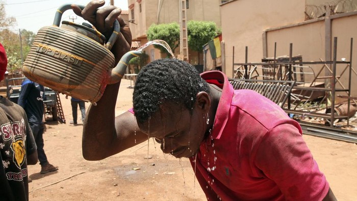 Warga Mali Kewalahan Hidup di Tengah Cuaca Panas Ekstrem Amadou Coulibaly, a 25-years-old, motorcycle taxi driver, drinks a sachet water to cool off under a blazing sun.in Bamako, Mali, Thursday, April, 18, 2024. Street vendors in Mali's capital of Bamako peddle water sachets, ubiquitous for this part of West Africa during the hottest months of the year. On Thursday, temperatures in Bamako reached 44 degrees Celsius (111 Fahrenheit) and weather forecasts say it's not letting up anytime soon. (AP Photo/Baba Ahmed)
