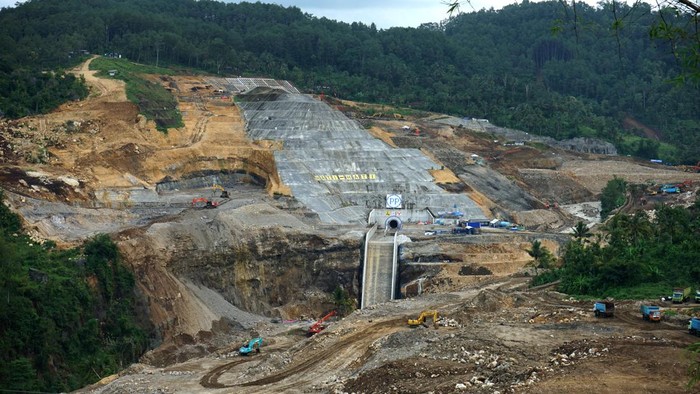 Begini Progress Terkini Proyek Bendungan Bagong Trenggalek Pengendara melintas dekat lokasi proyek pembangunan Bendungan Bagong, Trenggalek, Jawa Timur, Sabtu (20/4/2024). Poyek strategis nasional (PSN) yang menyedot anggaran Rp1,6 triliun yang telah dimulai sejak 2015 dan ditargetkan rampug pada akhir 2024 tersebut diproyeksikan mampu menampung 17,5 juta meter kubik air sehingga bisa efektif mengendalikan dampak banjir di wilayah Kota Trenggalek dan sekitar, sekaligus meningkatkan cakupan daerah irigasi pertanian seluas 857 hektare di daerah tersebut. FOTO/Destyan Sujarwoko/YU