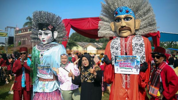 Warga berfoto dengan ondel-ondel saat mengikuti kegiatan budaya Lebaran Kukusan di Kawasan Kukusan, Depok, Jawa Barat, Sabtu (20/4/2024). Silahturahmi bertema Lebaran Kukusan dengan kegiatan makan bersama itu merupakan napak tilas suasana Lebaran suku Betawi tempo dulu yang bertujuan untuk melestarikan budaya daerah . ANTARA FOTO/Yulius Satria Wijaya/Spt.