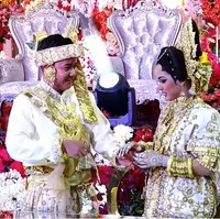 Sementara itu, pengantin pria Abdul Azis memakai Baju Jas Tutu’ putih yang juga dihiasi bordiran emas. Dia mengenakan hiasa kepala bernama sigara. Foto: YouTube Putri Isnari