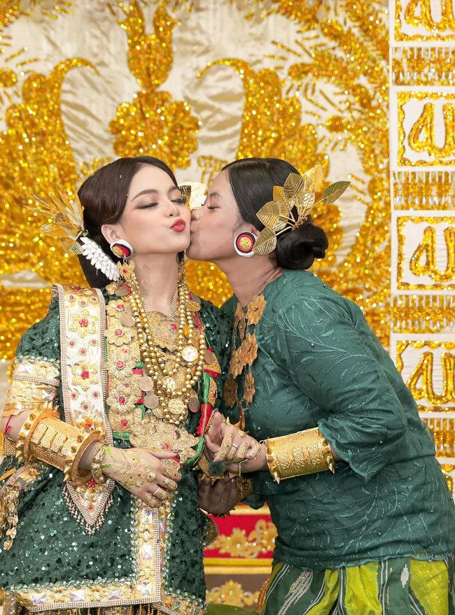 Saat Malam Mappacci, penyanyi 20 tahun ini mengenakan riasan wajah bernuansa coklat emas dengan pulasan lipstik merah terang. Dia mengenakan baju khas Mandar berupa atasan lengan pendek dipadu Lipaq Saqbe, sarung dengan motif tenun Mandar sebagai bawahan. Foto: Instagram/@da4_putri03