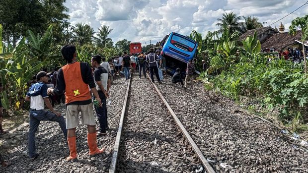 Warga mengamati kondisi bus penumpang Putra Sulung yang tertabrak kereta api Rajabasa di perlintasan tanpa palang pintu di Jalan Pertanian, Kecamatan Martapura, Kabupaten OKU Timur, Sumatera Selatan, Minggu (21/4/2024). Data sementara dari petugas di lapangan, sebanyak tiga penumpang bus meninggal dunia dan penumpang lainnya mengalami luka-luka. ANTARA FOTO/T Fikri W/Lmo/Spt.