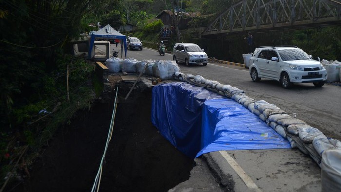 Kendaraan melintasi badan jalan nasional yang amblas di kelok hantu Aia Angek, Tanah Datar, Sumatera Barat, Minggu (21/4/2024). Jalan Raya Padang-Bukittinggi yang terdampak banjir lahar dingin Gunung Marapi dua pekan lalu itu kini amblas sehingga arus lalu-lintas dilakukan sistem buka tutup. ANTARA FOTO/Iggoy el Fitra/wpa.