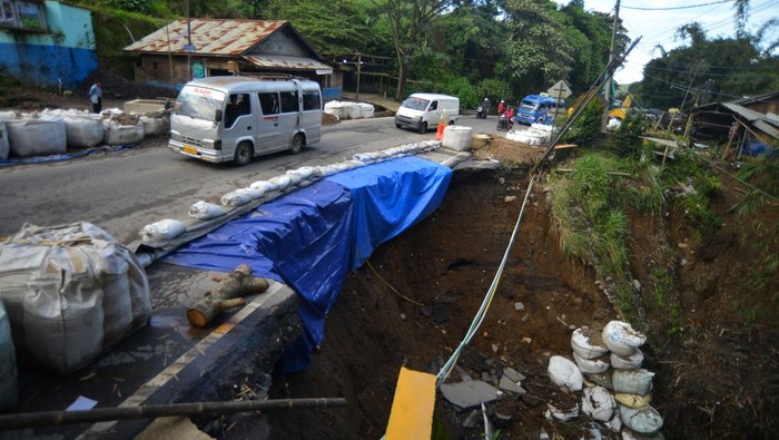 Kendaraan melintasi badan jalan nasional yang amblas di kelok hantu Aia Angek, Tanah Datar, Sumatera Barat, Minggu (21/4/2024). Jalan Raya Padang-Bukittinggi yang terdampak banjir lahar dingin Gunung Marapi dua pekan lalu itu kini amblas sehingga arus lalu-lintas dilakukan sistem buka tutup.  ANTARA FOTO/Iggoy el Fitra/wpa.