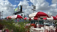 Memang restoran ini kecil, tetapi mereka juga punya pilihan tempat duduk di bagian luar yang setiap mejanya dilengkapi payung seperti ini. Membuat pelanggan nyaman menikmati hot dognya. Foto: Google Review / MAY
