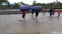 Setelah tiba di sungai, petugas dibantu warga memanggul logistik menyeberangi aliran lahar sungai Regoyo sepanjang 100 meter.