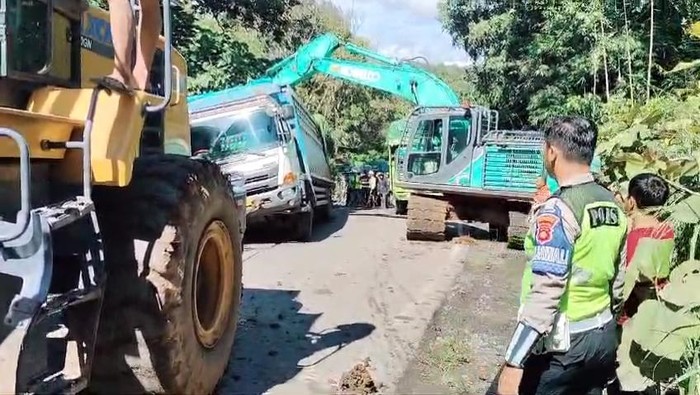 Proses evakuasi mobil truk pengangkut batu bara yang terperosok menggunakan alat berat.