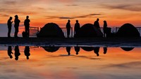 Wisatawan mengamati matahari terbit saat berkemah di areal Embung Bansari kawasan lereng Gunung Sindoro, Bansari, Temanggung, Jawa Tengah, Minggu (21/4/2024).