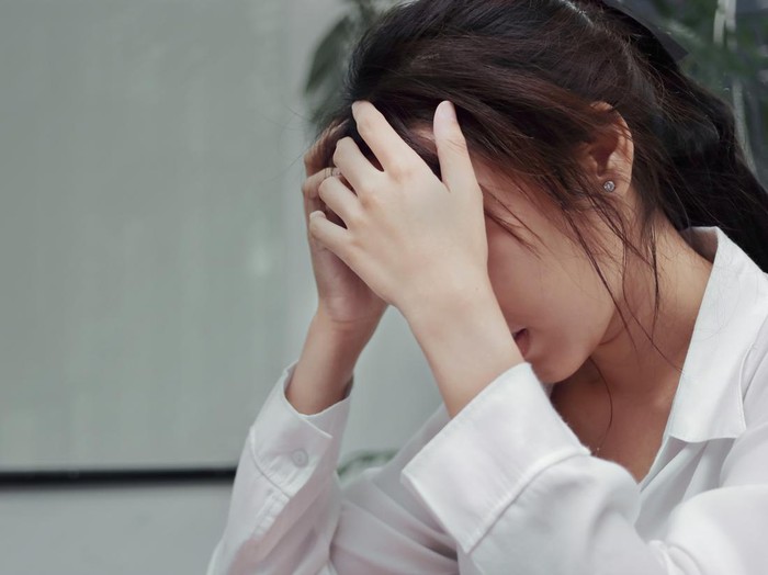 Stressed exhausted young Asian business woman suffering from severe depression in office.