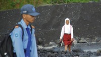 Siswa sekolah dasar (SD) melintasi daerah aliran sungai (DAS) Kali Regoyo untuk berangkat sekolah di Desa Jugosari, Kecamatan Candipuro, Lumajang, Jawa Timur, Senin (22/4/2024).  