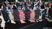 Massa membawa atribut aksi seperti spanduk dan poster.