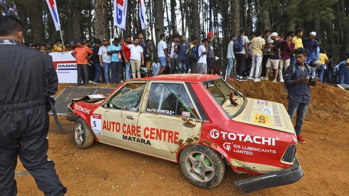 Horor Kecelakaan Balap Mobil di Sri Lanka, 7 Orang Tewas dan Puluhan Luka People gather around a car that had crashed into the spectators during the Fox Hill Supercross, a motor racing event organized by the Sri Lanka's army, in Diyatalawa, Sri Lanka, Sunday, April 21, 2024. (AP Photo/STR)