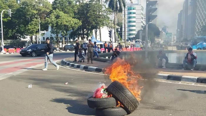 Massa pedemo bakar ban dan spanduk bergambar wajah 9 hakim MK di Patung Kuda, Jakpus, Senin (22/4/2024).