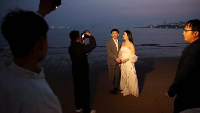 Pantai Ini Jadi Lokasi Prewedding Favorit Warga China Couples take part in their pre-wedding photoshoots by the sea in Qingdao, Shandong province, China April 21, 2024. REUTERS/Florence Lo TPX IMAGES OF THE DAY