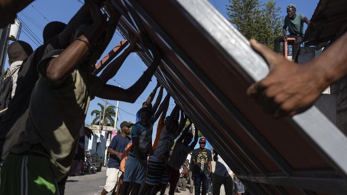 Neighbors raise a metal gate as they work to install it as a barricade against gangs, in the Petion-Ville neighborhood of Port-au-Prince, Haiti, Saturday, April 20, 2024. (AP Photo/Ramon Espinosa)