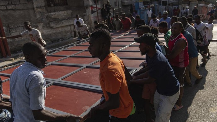 Potret Perjuangan Warga Haiti Bertahan Hidup Saat Kekerasan Geng Meningkat Neighbors raise a metal gate as they work to install it as a barricade as protection against gangs, in the Petion-Ville neighborhood of Port-au-Prince, Haiti, Saturday, April 20, 2024. (AP Photo/Ramon Espinosa)