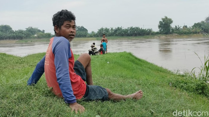 Sodik, salah satu korban selamat perahu penambang pasir di Bojonegoro menunggu proses evakuasi di tepi bengawan