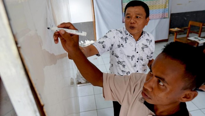 Berantas Buta Aksara, Puluhan Warga Binaan di Lapas Gorontalo Belajar Baca Tulis Seorang warga binaan pemasyarakatan (WBP) menjadi tenaga pengajar baca tulis di Lembaga Pemasyarakatan (Lapas) Kelas IIA, Kota Gorontalo, Gorontalo, Selasa (23/4/2024). Lapas Kelas IIA Gorontalo menjalankan program pemberantasan buta aksara yaitu membaca dan menulis bagi warga binan yang dilakukan empat kali dalam satu pekan yang diikuti oleh 30 orang dan dibagi dalam dua kelas belajar. ANTARA FOTO/Adiwinata Solihin/aww.