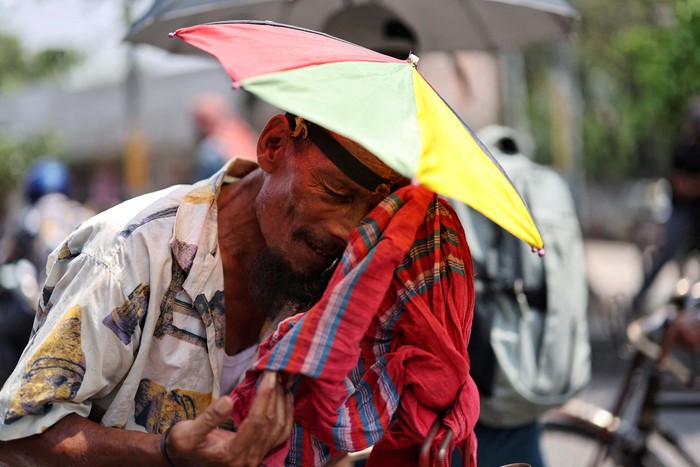 A man, wearing a plastic sheet on his head to get shade from the sun, drinks water during the countrywide heatwave in Dhaka, Bangladesh, April 22, 2024. REUTERS/Mohammad Ponir Hossain