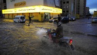Seorang pria mengendarai sepeda motor di jalan yang banjir setelah hujan lebat di Sanaa, Yaman, Senin (22/4/2024).