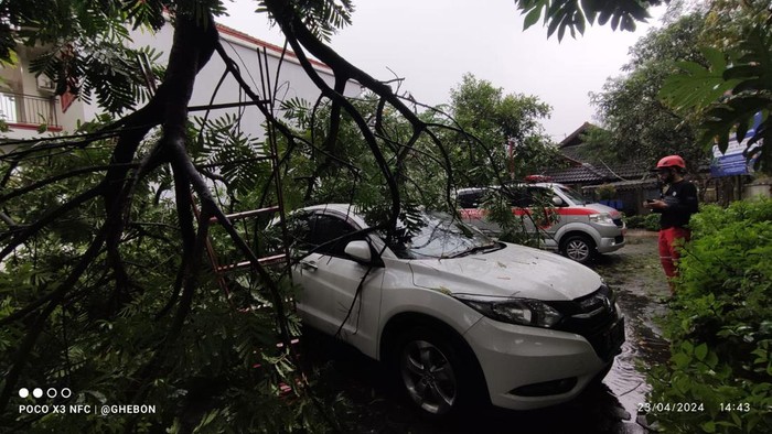 Mobil tertimpa patahan batang pohon usai hujan angin di Sleman, Selasa (23/4/2024).