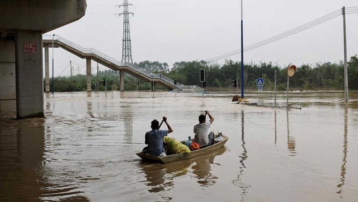 Residents row a boat on the floodwaters following heavy rainfall, at the Xiashahe village, in Qingyuan, Guangdong province, China April 22, 2024. REUTERS/Tingshu Wang