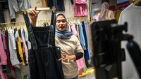 Pedagang kembali berjualan di pasar tersebut. Tampak salah satu pedagang sedang menawarkan pakaian secara daring.  
